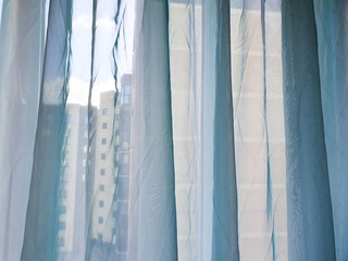 Curtains against the backdrop of a view from an apartment or city house window. Sheer curtains on a house window, bedroom, or room, a cozy space for relaxation.