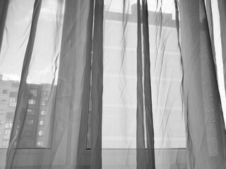 Curtains against the backdrop of a view from an apartment or city house window. Sheer curtains on a house window, bedroom, or room, a cozy space for relaxation.