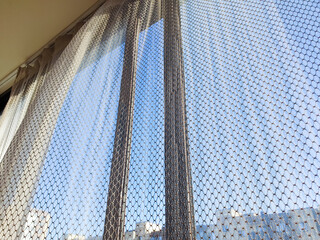 Curtains against the backdrop of a view from an apartment or city house window. Sheer curtains on a house window, bedroom, or room, a cozy space for relaxation.
