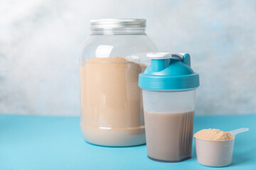 Protein shake with protein powder on a colored background. The powder is mixed with water or milk. A dietary supplement for a balanced diet. Whey protein. Fitness and gym diet nutrition.