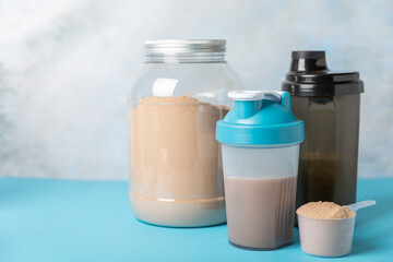 Protein shake with protein powder on a colored background. The powder is mixed with water or milk. A dietary supplement for a balanced diet. Whey protein. Fitness and gym diet nutrition.