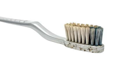 A worn toothbrush with frayed bristles, showcasing significant usage and a build-up of residue on the bristle head.