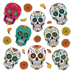 Colorful sugar skulls with floral designs and leaves on a white background, flat lay composition with vibrant hues.
