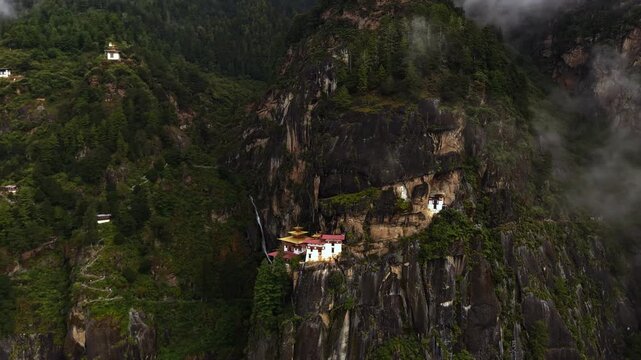 Aerial view of Tigers Nest Monastery perched dramatically on a cliffside amid lush greenery and shrouded in ethereal mist, Paro, Bhutan.