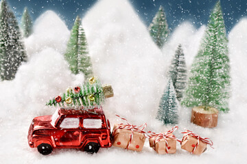 Red car with Christmas presents and tree on the top driving on a snow-covered road