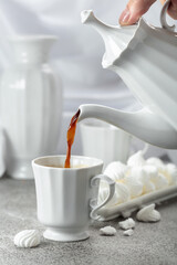 Black coffee in white porcelain cup and white small French meringues.