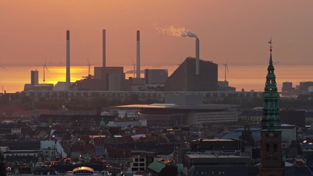 Aerial drone view of the skyline of Copenhagen, Denmark with Amager Bakke and offshore wind turbines at sunrise
