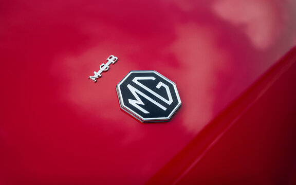 MG logo on red car - close-up view. Octagonal british car emblem on the trunk of 1960s MGB roadster. Kyiv, Ukraine - September 30 2024