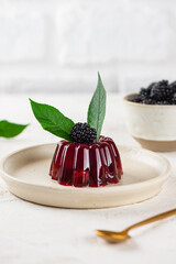 Delicious jelly with cherry, blackberry and green cherry leaves in a light table. Healthy food, sugar, gelatin and lactose free. Vertical orientation.