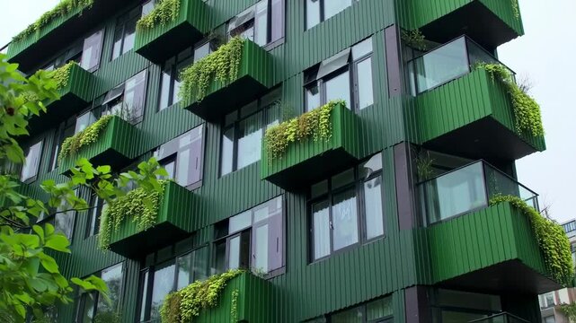 Modern green apartment building with vertical cladding and planted balconies
