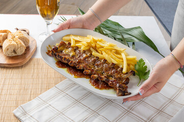 Hands serving barbecue pork ribs and french fries meal