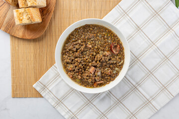 Hearty lentil soup with bread on bamboo mat