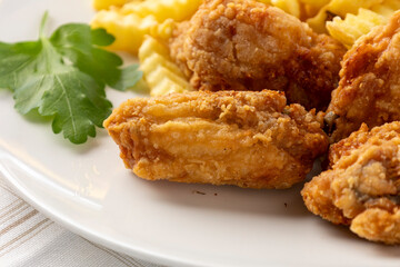 Crispy fried chicken wings with golden french fries and parsley