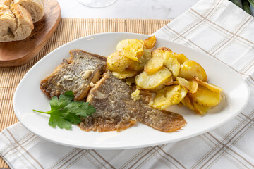 Fried fish fillets and potatoes served on white plate