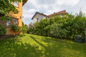 Charming Backyard Garden With Green Foliage and Adjacent Residential Houses