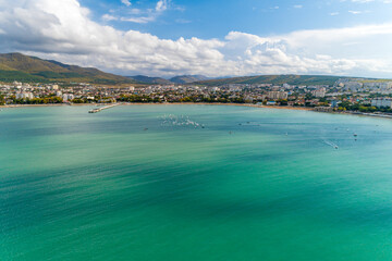 Naklejka premium Yacht competitions in Gelendzhik Bay. Many small yachts on water. Aerial view. Caucasus Mountains in background. Children's regatta