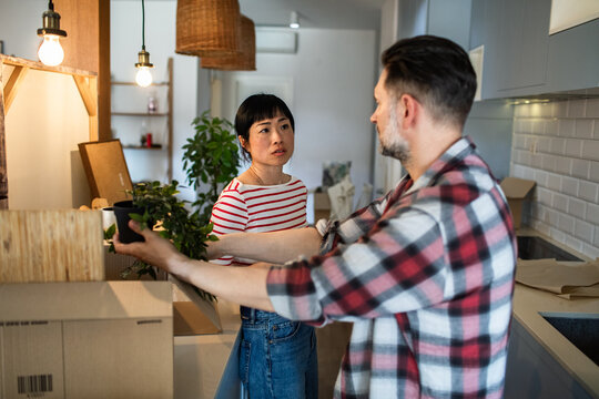 Young couple talking while unpacking in their new home after moving in