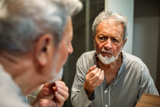 Senior man looking worried in mirror