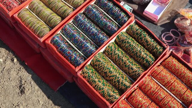 Vibrant rows of traditional Indian bangles neatly arranged for sale at a local village mela. The outdoor fair setting highlights culture, craft, and festive rural charm.