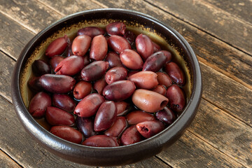 A bowl with pitted kalamata olives on rustic wooden table.