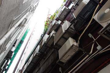 Air conditioner compressor and electrical wires. Cooling pump technology for home or office. Air conditioning pipes heat pumps see electrical circuit board on wall gap between buildings.