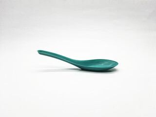 Turquoise spoon sits on a stark white background in a studio setting highlighting its color and form for culinary or product design concepts.