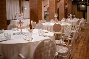 Elegant Wedding Reception Dining Hall Setup with Round Tables Covered in White Linens and Fancy Chairs Ready for Guests to Celebrate Special Occasion
