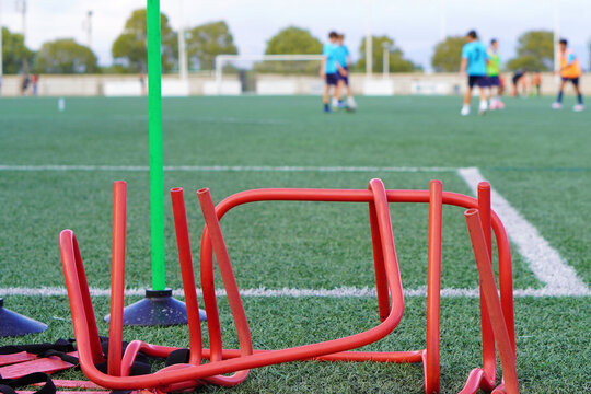 Children's sports. Soccer training hurdles and cones, and children training on the field.