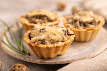 Tartlets with meat and cheese on brown concrete, linen textile. side view, close up, selective focus