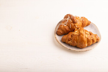 Croissant on blue plate on white wooden, side view copy space