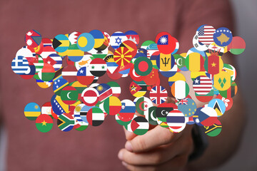 Hand holding a cluster of global flags representing international cooperation, understanding, and unity. Ideal for themes of globalization, worl