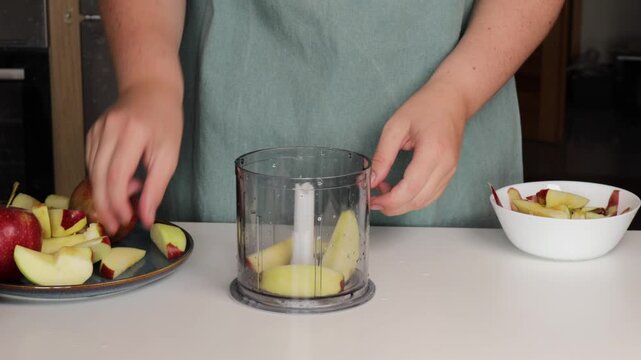 A woman throws apples into a blender bowl. making a pie
