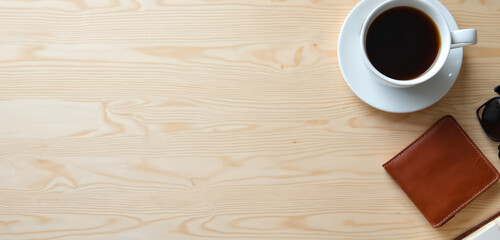 Obraz premium Overhead view shows table with coffee sunglasses and wallet. Light wooden texture background. Lifestyle concept. Drink in cup and place for notes. Good morning mood with fashion style elements.