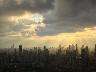 Fototapeta premium high angle view of Shanghai city skyline under heavy cloud with crepuscular ray of sunlight breaking through