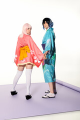 Trendy cosplay couple in kimonos posing together in a studio setting