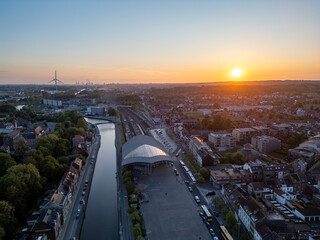 Halle, Vlaams Brabant, Belgium, 6th of May, 2025, A breathtaking sunset over a vibrant city illuminates its intricate architecture and enhances serene waterways