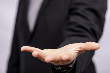 Fototapeta premium A close-up of a businessman's open hand, inviting the viewer, representing concepts of offering, invitation, or giving, against a neutral backgr