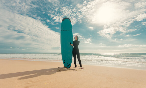 Surfer. Teenage girl learning to surf on foam in the ocean. First surfing lesson. Amateur surfer. Surfing training. Photo for surfing school advertising on social media.