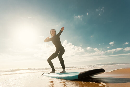 Surfer. Teenage girl learning to surf on foam in the ocean. First surfing lesson. Amateur surfer. Surfing training. Photo for surfing school advertising on social media. - Powered by Adobe