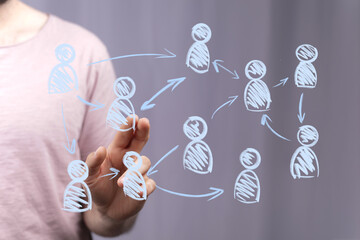 A person's hand interacts with a futuristic digital interface displaying a network of connected human icons, symbolizing teamwork, communication