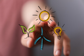 Hand interacting with virtual icons representing sustainable energy sources: plant, sun, wind...