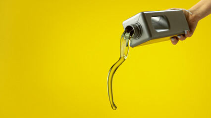Stream of golden motor oil pouring from plastic container on yellow background. Concept of lubricant quality, automotive maintenance, fuel efficiency, and professional service industry visuals.