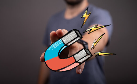 Powerful image of a hand holding a magnet, symbolizing attracting customers, clients, or success.