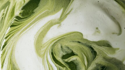 Close-up of creamy green matcha tea swirling with white milk, creating a dynamic and textured abstract marbled pattern suitable for food, beverage, and culinary backgrounds.