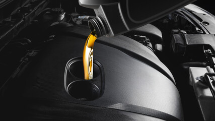 Golden motor oil pouring into modern car engine close-up under hood. Concept of automotive...