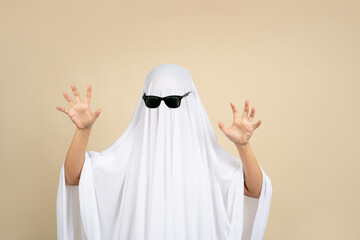 Woman in ghost costume on dark beige background celebrating Halloween