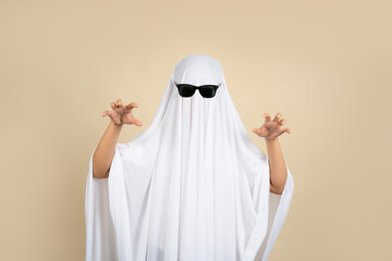 A person in a white ghost costume on a beige background.
