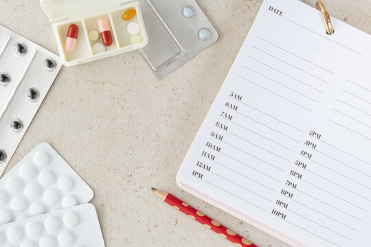 Flat lay composition with pill box, blister packs and medical schedule list on light background, healthcare and pharmaceutical concept showing treatment, prevention and medication organization