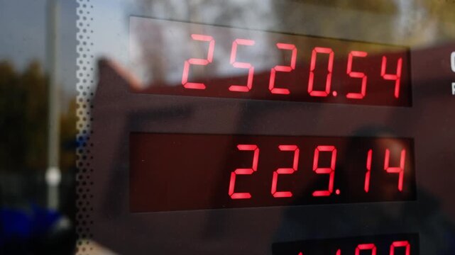 Close-up of a digital fuel price display showing various prices. The setting conveys a typical gas station atmosphere.