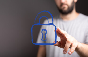 Stock photo of a man interacting with a digital padlock, illustrating cybersecurity, data...
